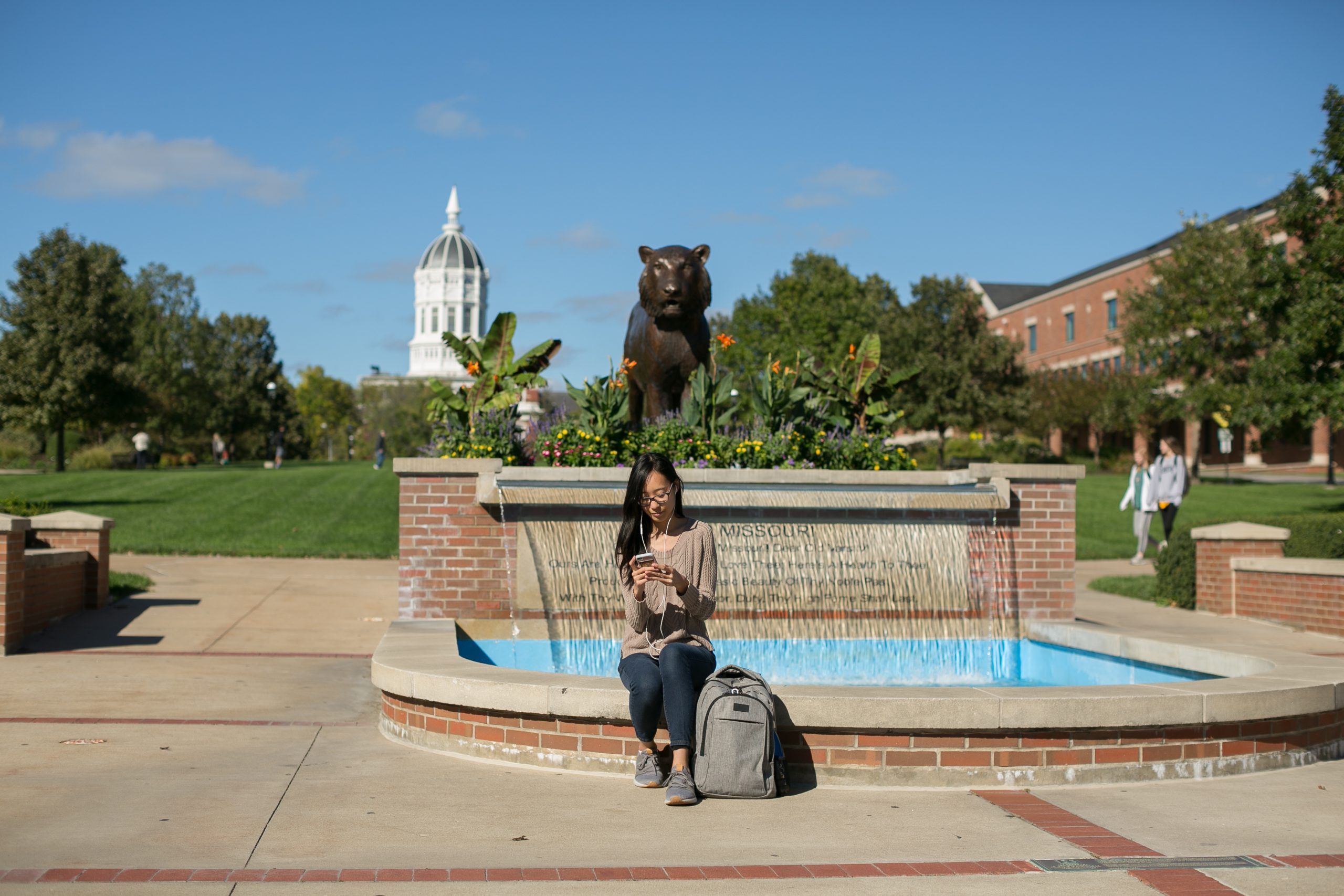 a woman sits in front of a fountain